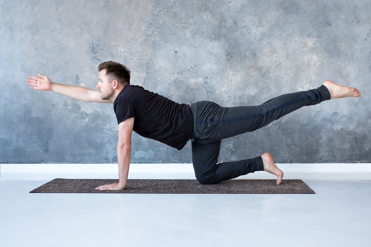 Young caucasian men practices yoga asana chakravakasana